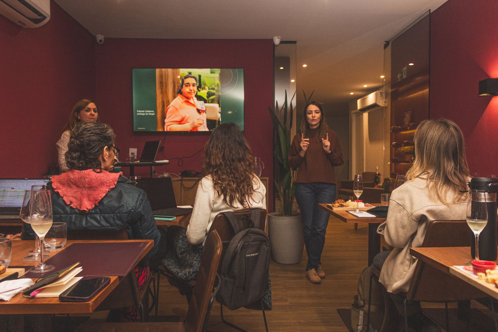 Mulheres com laptops acompanhando uma apresentação presencial da Claud.IA